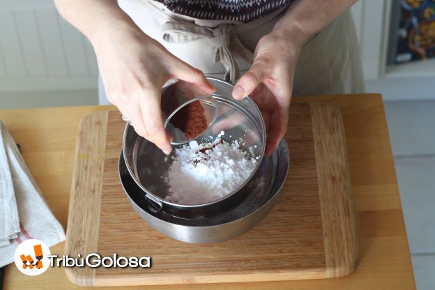 Mettete lo zucchero a velo e il cacao in un setaccio su una ciotola.